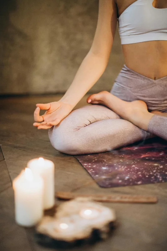 femme assise en lotus sur son tapis de yoga pour une séance de méditation 