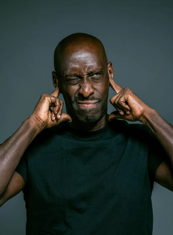 man covering his ears with his hands because of noise