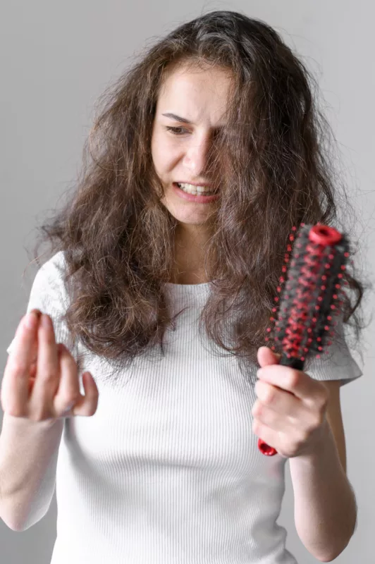 femme qui constate ses cheveux cassés, réparer ses cheveux abimés par le soleil